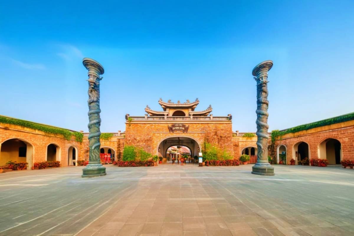 Ancient Vietnamese architectural courtyard with red brick walls, ornate pillars, and traditional upturned roof featuring deco