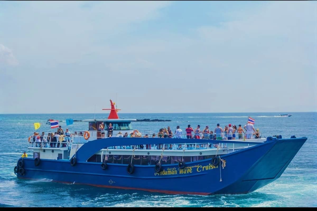 Blue and red passenger ferry boat loaded with tourists in tropical waters between Phuket and Krabi, Thailand
