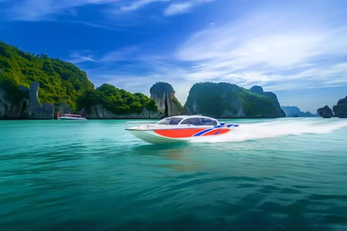 Red and white speedboat in turquoise water with limestone cliffs and karst formations in Phang Nga Bay, Thailand