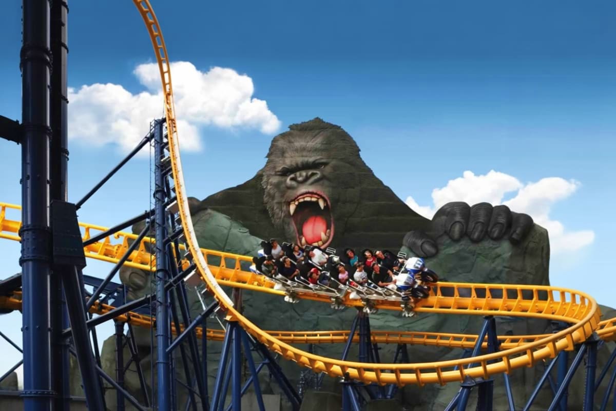 Trans Studio Bali Roller coaster ride with passengers passing by giant King Kong statue at Trans Studio Bali theme park