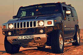 Hummer Desert Safari Abu Dhabi Black Hummer H2 vehicle parked on sandy desert terrain during golden hour in Abu Dhabi