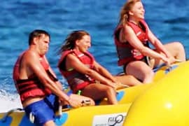 Family enjoying banana boat ride on blue water with yellow inflatable tube