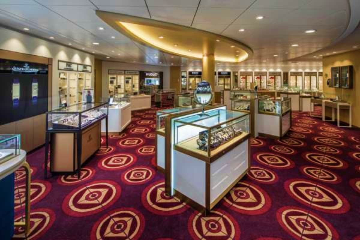 Luxury jewelry store interior aboard cruise ship with glass display cases, red patterned carpet, and golden ceiling elements
