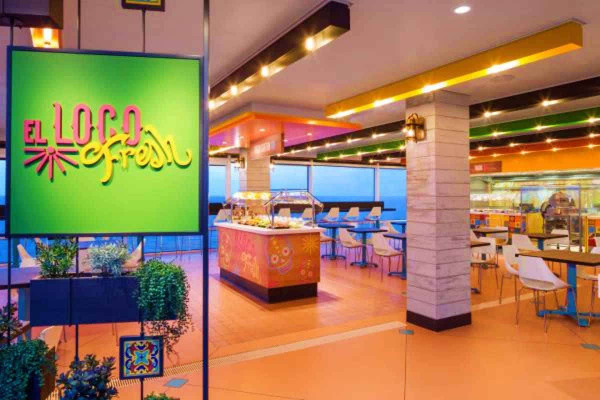 El Loco Fresh restaurant interior on Odyssey of the Seas with green neon signage, orange floors, and colorful modern dining s