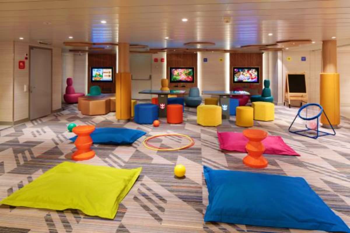Colorful children's play area on cruise ship with floor cushions, foam toys, climbing structures, and entertainment screens
