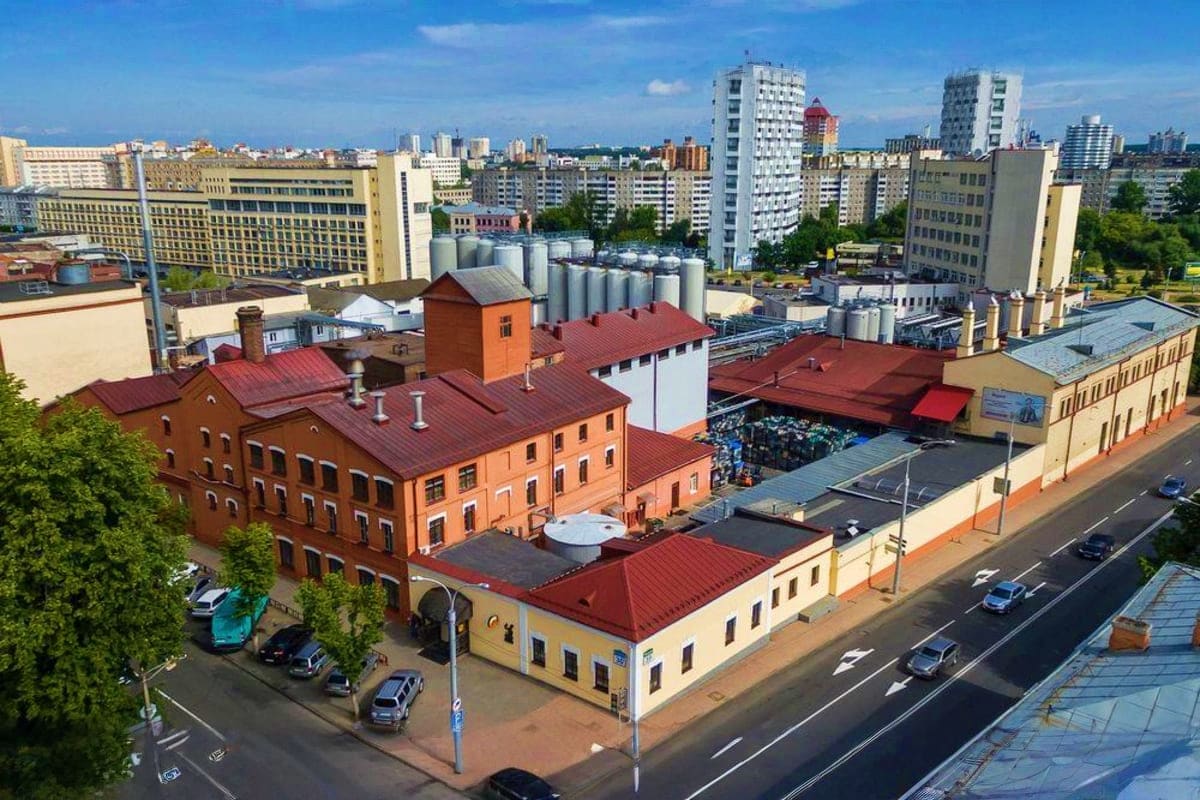 Aerial view of historic brick building with red roof in Minsk city center surrounded by modern residential towers and urban s