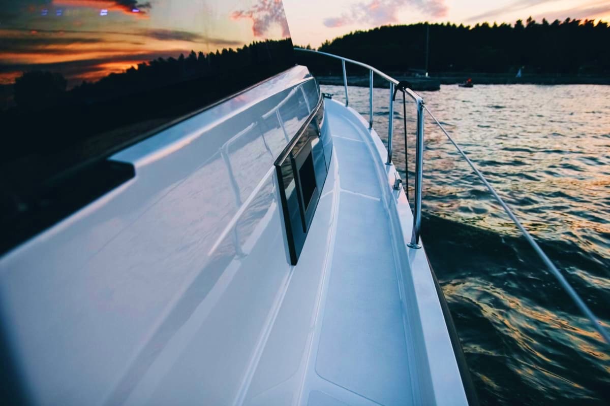 Minsk Highlights with Luxury Experiences White luxury yacht with metal railing on calm lake at sunset, forested shoreline in background