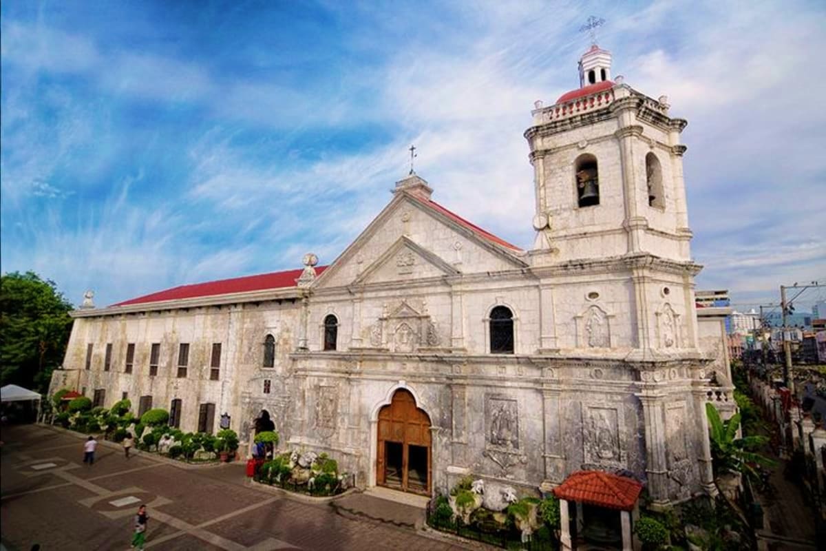 Historic white stone church with red roof and bell tower in Cebu, Philippines, showing colonial Spanish architecture and plaz