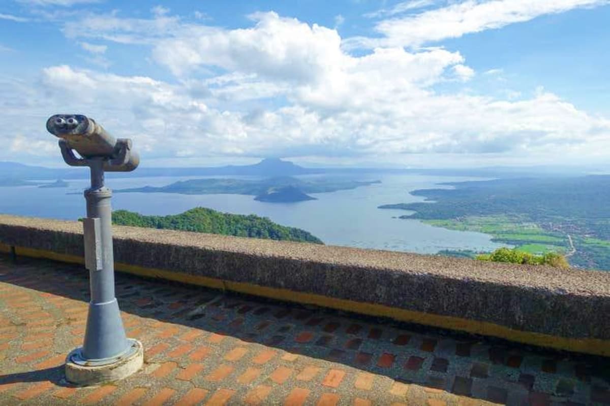 Coin-operated telescope at mountain viewpoint overlooking Taal Lake and volcanic island in Batangas, Philippines