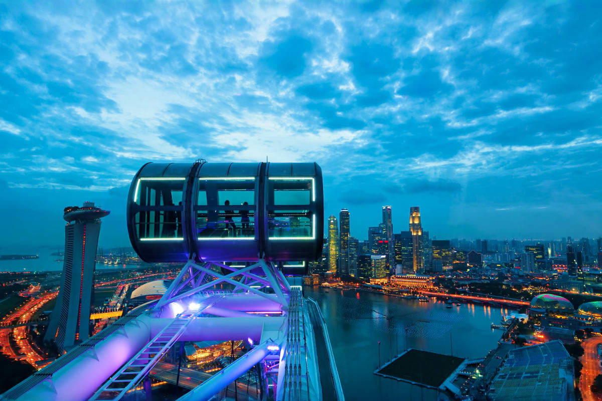 Sentosa Island & City Escape Illuminated ferris wheel capsules overlooking Singapore's cityscape and harbor at dusk with glowing skyscrapers