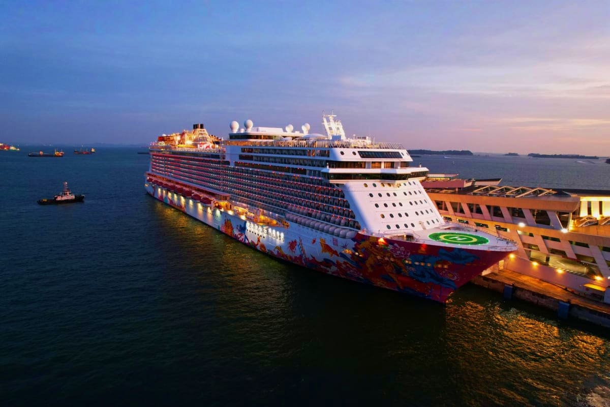 Dream Honeymoon Cruise Vacation Large cruise ship docked at port during twilight with illuminated hull and superstructure against blue evening sky