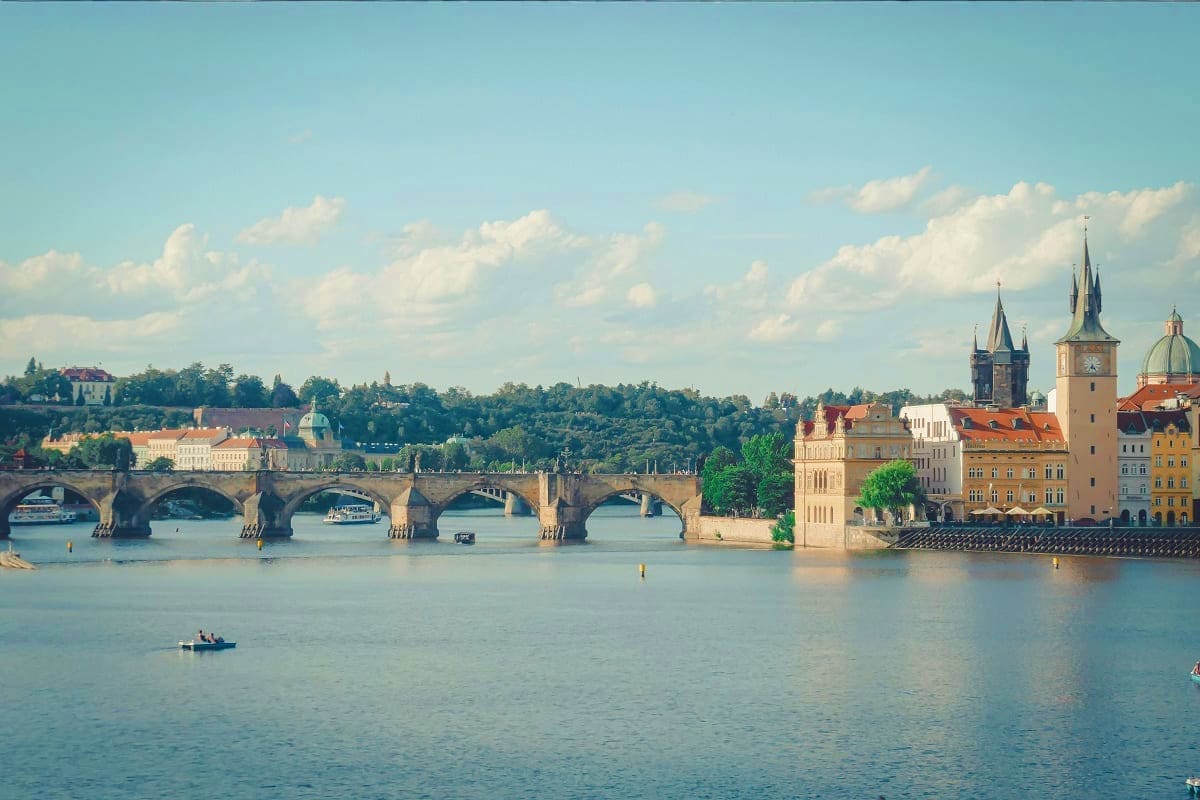 Charles Bridge spanning the Vltava River in Prague with historic towers, church spires, and colorful buildings along the wate