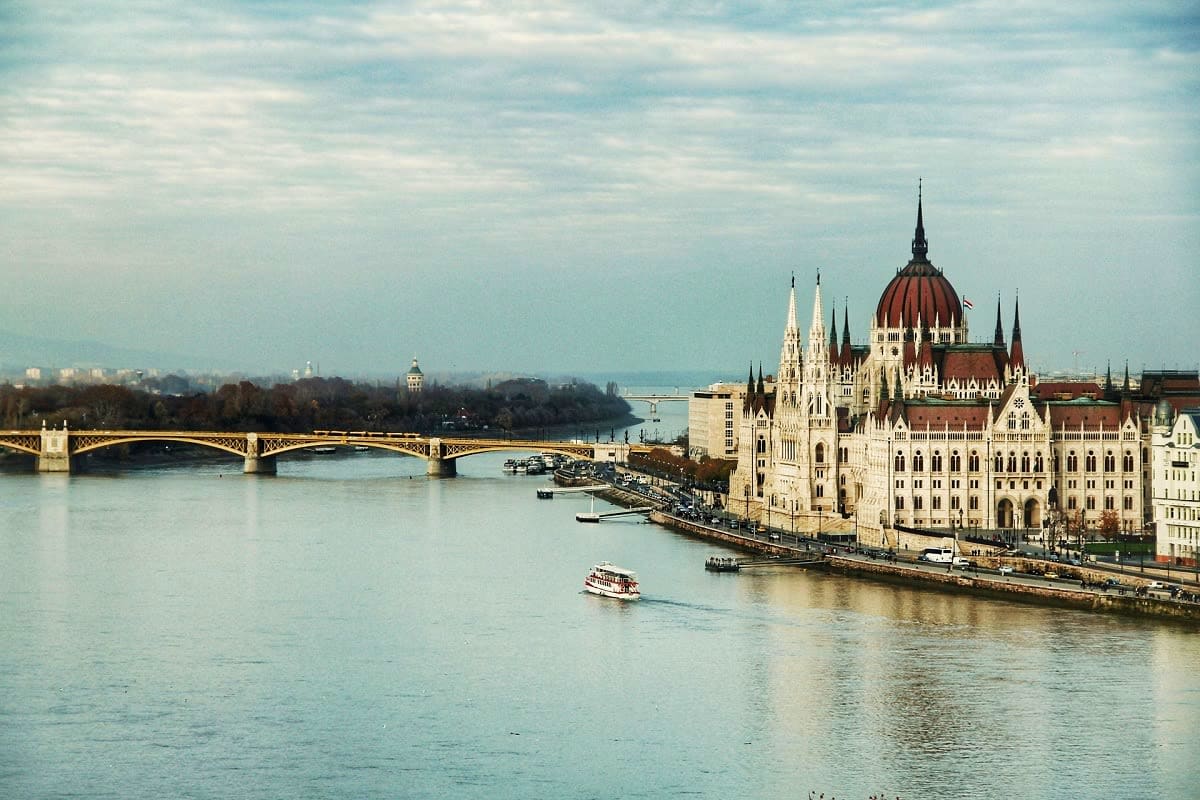 Hungarian Parliament Building with red dome overlooking the Danube River with Margaret Bridge and tourist riverboat in Budape