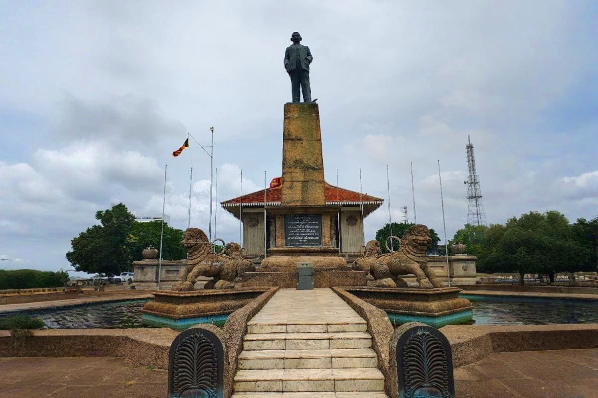 Historical and Cultural Tour Monument statue standing on elevated stone base with decorative lion sculptures, reflecting pool, and ornamental gateway stru