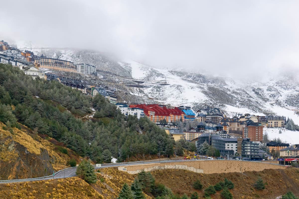 Exotic Kazakhstan Christmas Special Alpine ski resort town nestled in snow-capped mountains with colorful hotels, evergreen forests, and winding mountain road