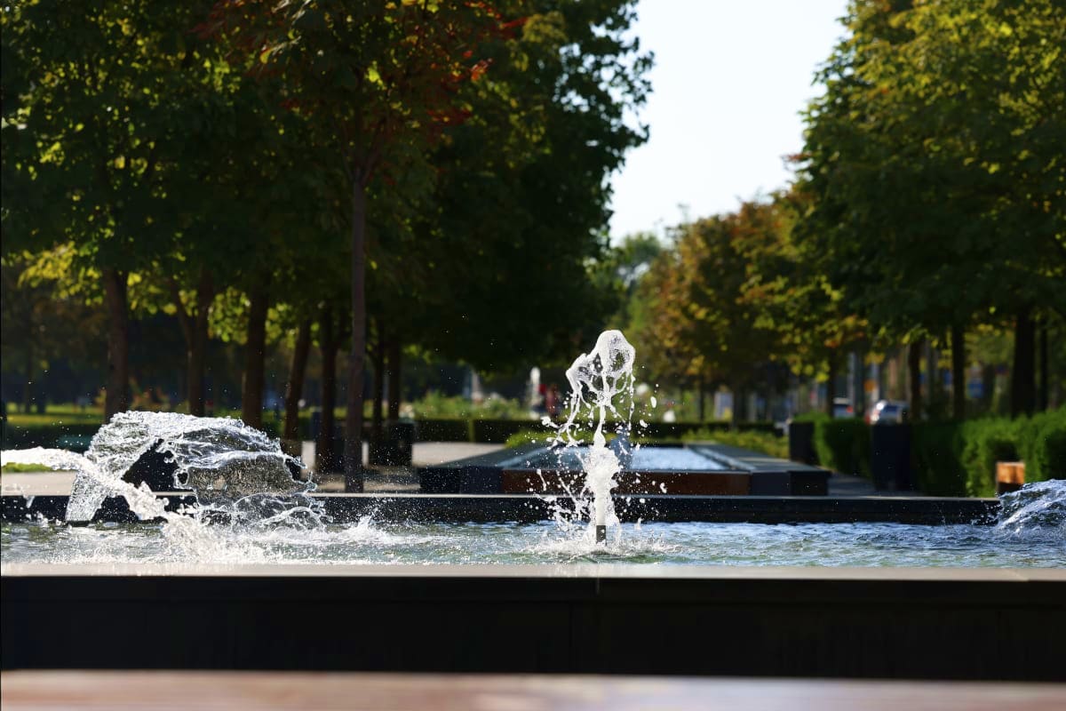 Explore Uzbekistan Christmas Special Water fountain splashing in a tree-lined park pathway in Uzbekistan during daytime