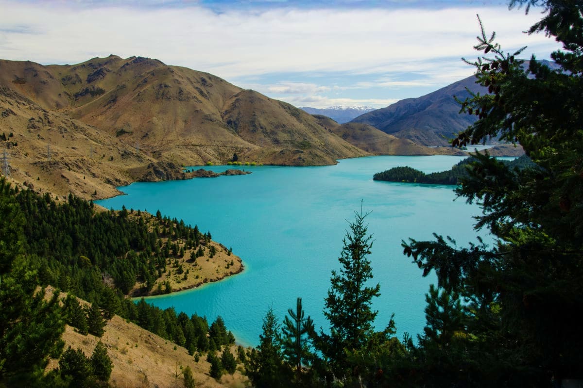 Turquoise alpine lake surrounded by bare mountains and evergreen forests in Armenia's high-altitude landscape