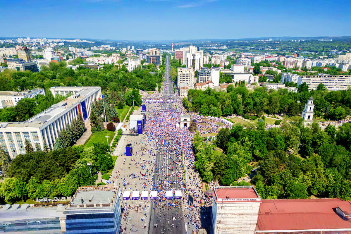 Aerial view of large crowd gathering in central square of Yerevan, Armenia with government buildings and green trees lining s