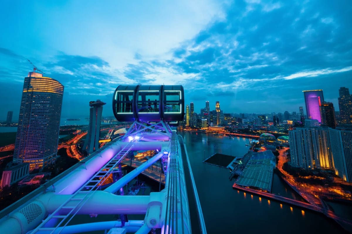 Singapore-Family-Fun-Package Ferris wheel cabin overlooking illuminated Singapore cityscape at dusk with harbor and skyscrapers