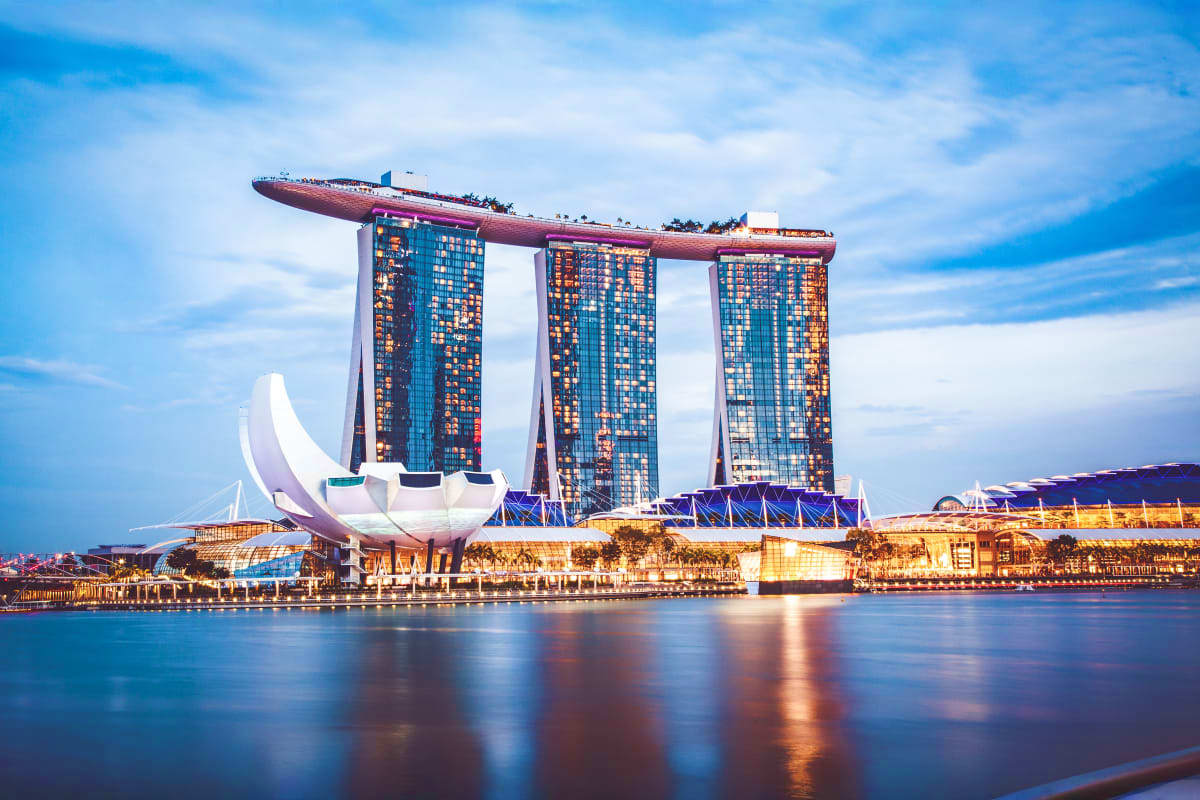 Singapore-Family-Fun-Package Marina Bay Sands Hotel with ship-shaped rooftop structure reflected in water at dusk, Singapore waterfront