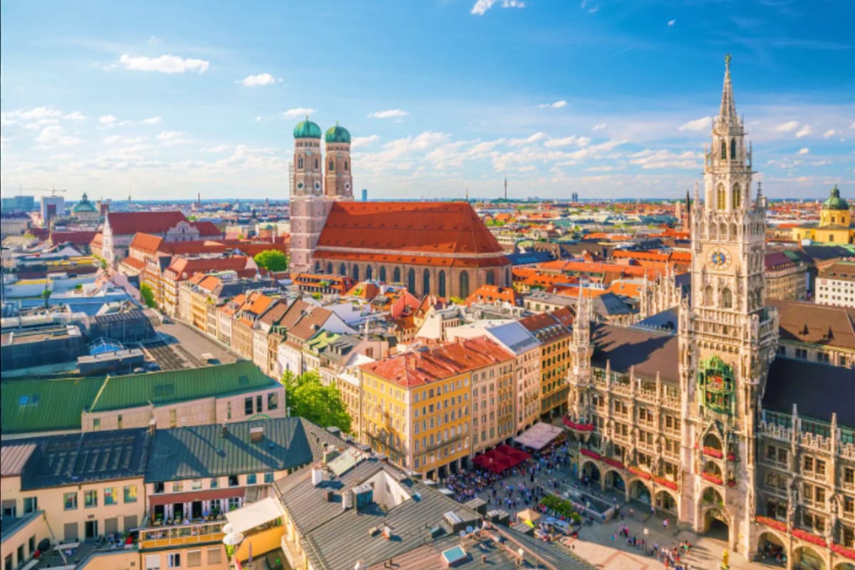 Aerial view of Munich's Marienplatz showing the Gothic New Town Hall tower, Frauenkirche church with green domes, and colorfu