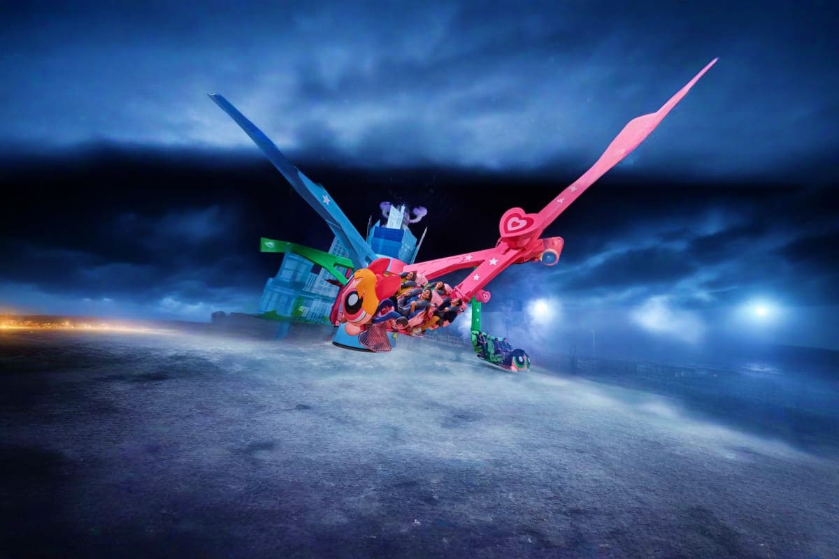 Colorful toy helicopter and building blocks on desert sand with dramatic stormy sky at dusk