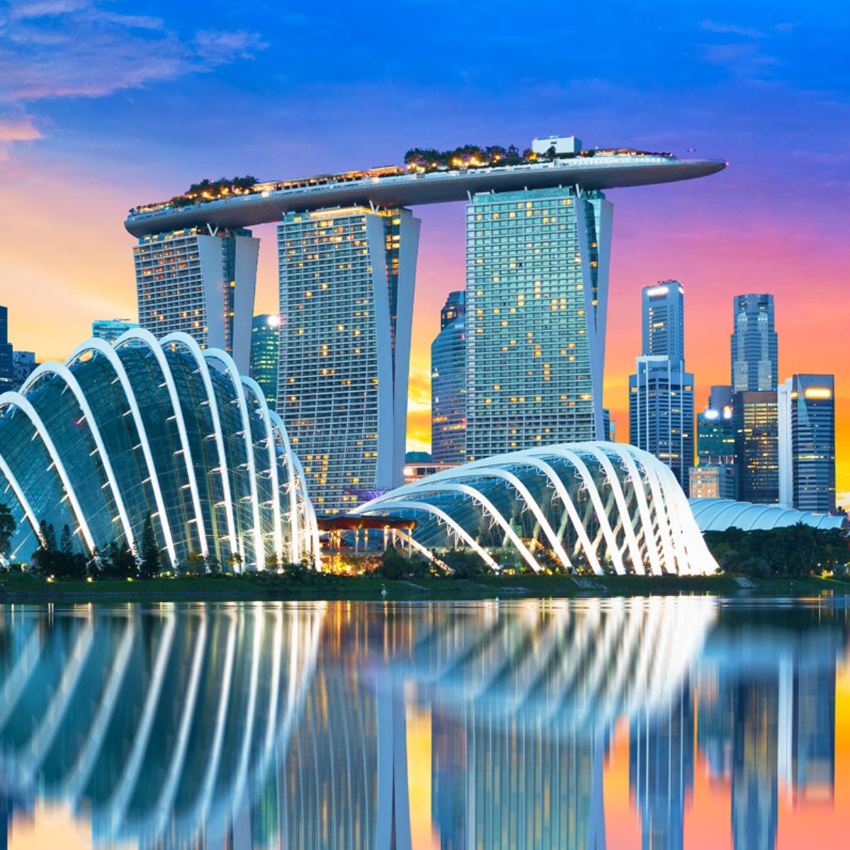 Marina Bay Sands hotel with Supertree Grove and skyline reflected in water at sunset, Singapore