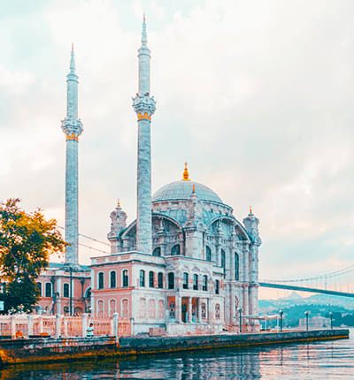 Ortakoy Mosque on the Bosphorus waterfront in Istanbul with two minarets and blue dome reflected in water