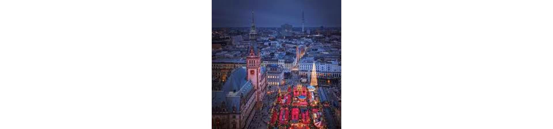Aerial view of Hamburg's historic city center at dusk with illuminated Christmas market stalls and church spires