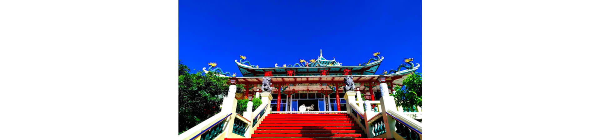 Traditional Chinese temple with ornate curved roof and gold dragons against blue sky in Cebu City, Philippines