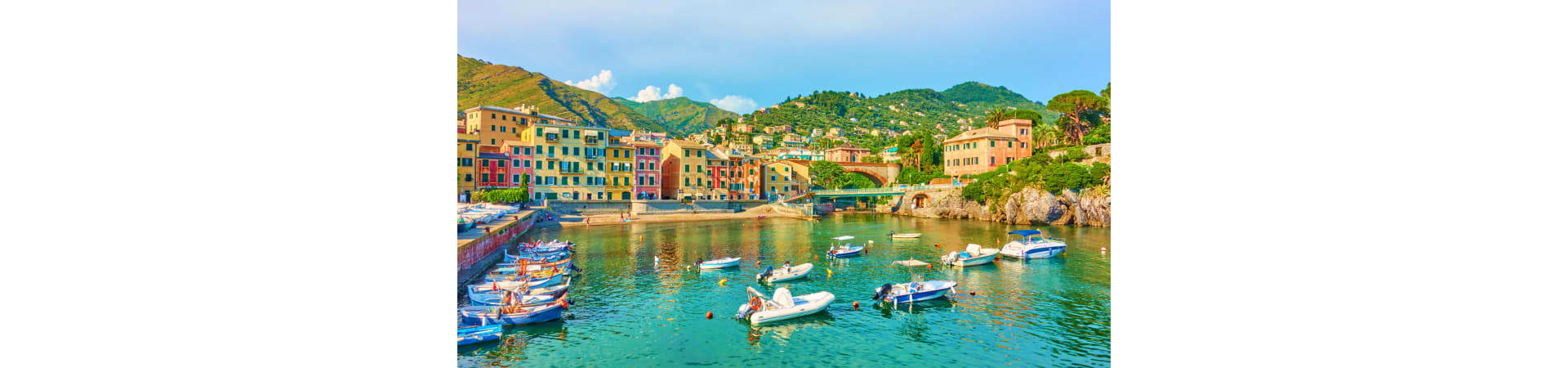 Colorful waterfront village with boats in turquoise water, hillside buildings, and green mountains, Cinque Terre Italy