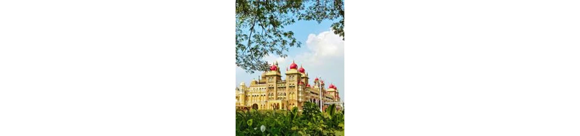 Mysore Palace with golden yellow walls and red domed turrets surrounded by green trees under blue sky