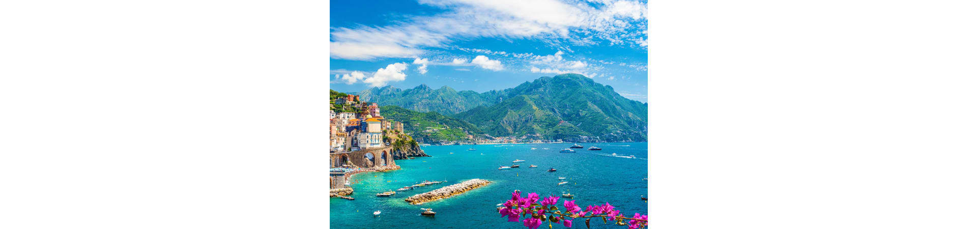 Atrani village on Amalfi Coast with colorful buildings, turquoise Mediterranean Sea, green mountains, and pink bougainvillea 