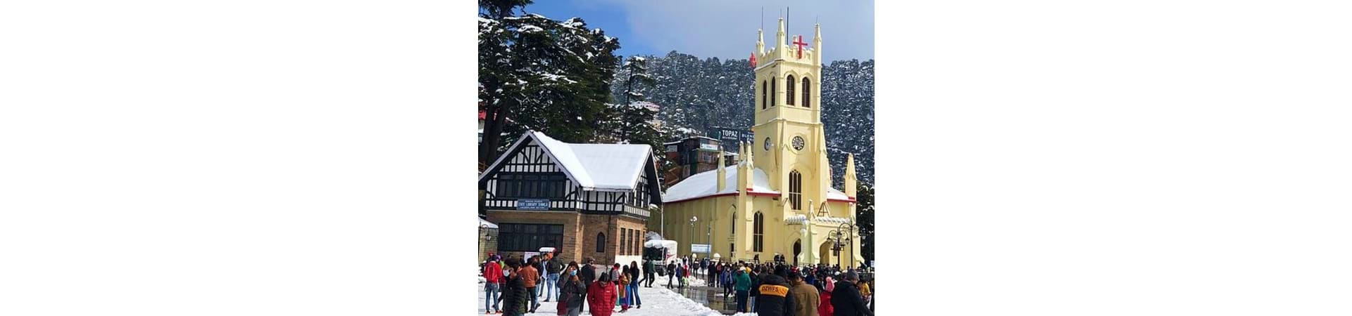 Christ Church Shimla with snow-covered timber-framed buildings and tourists in the town square during winter