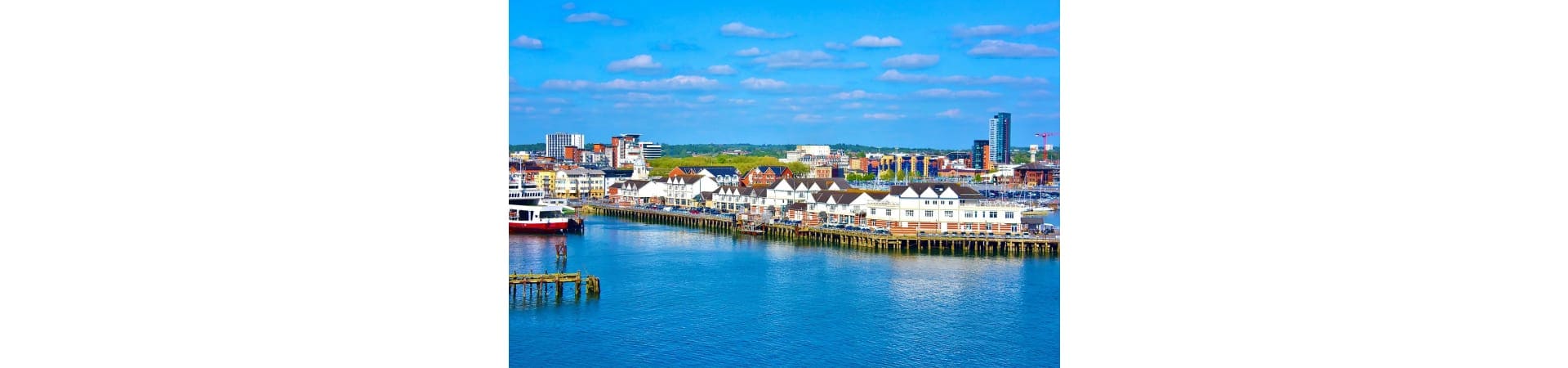 Southampton waterfront with white buildings, container ship, and city skyline along the English coast
