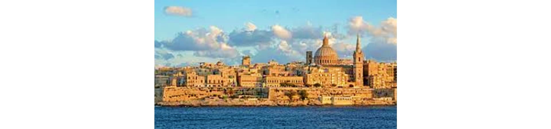 Valletta skyline with golden limestone buildings and St. Paul's Cathedral dome overlooking the Mediterranean Sea