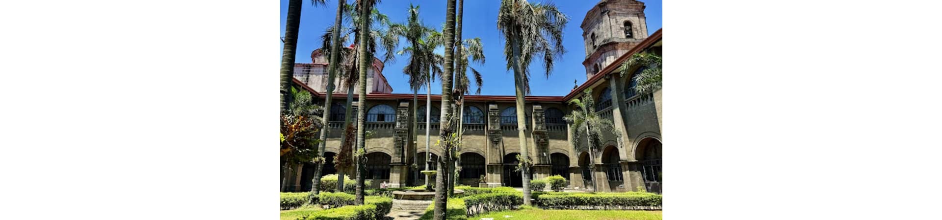 Historic Spanish colonial courtyard with palm trees and stone architecture in Manila, Philippines