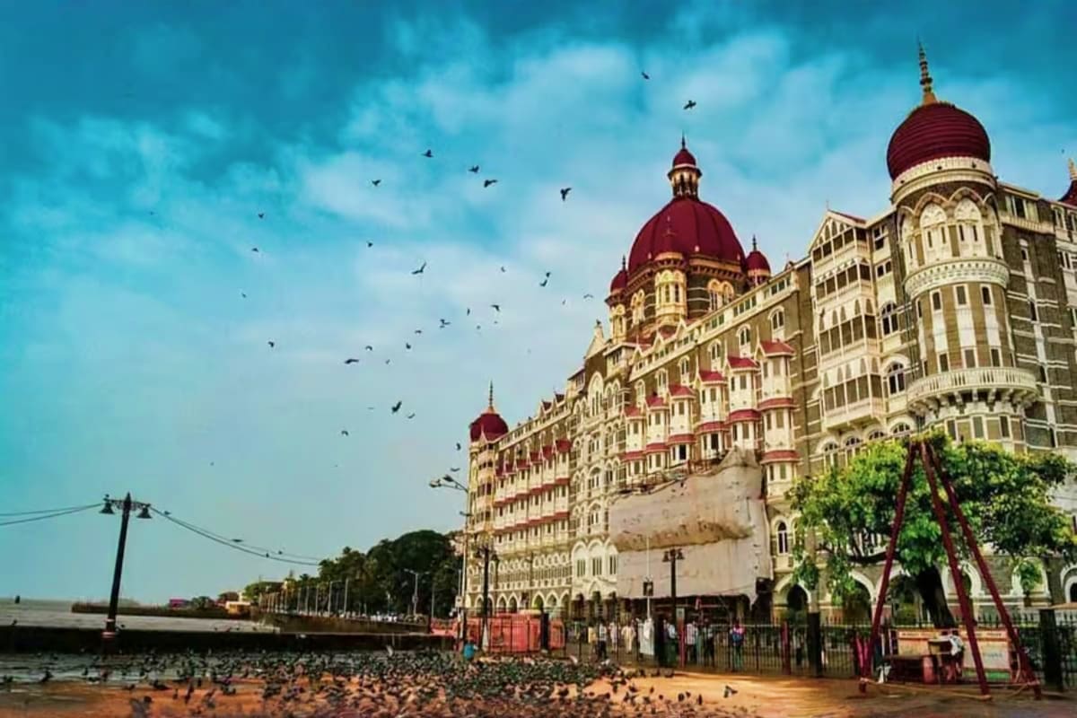Testing DCC web test Taj Mahal Palace Hotel in Mumbai with red domes, beachfront location, and birds flying overhead under blue sky