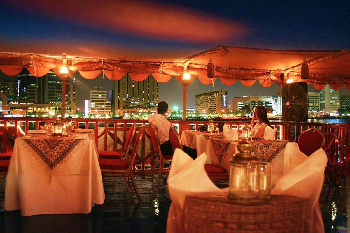 Testing DCC web test Rooftop dinner tables with white linens overlooking illuminated city skyline at night under orange fabric canopy