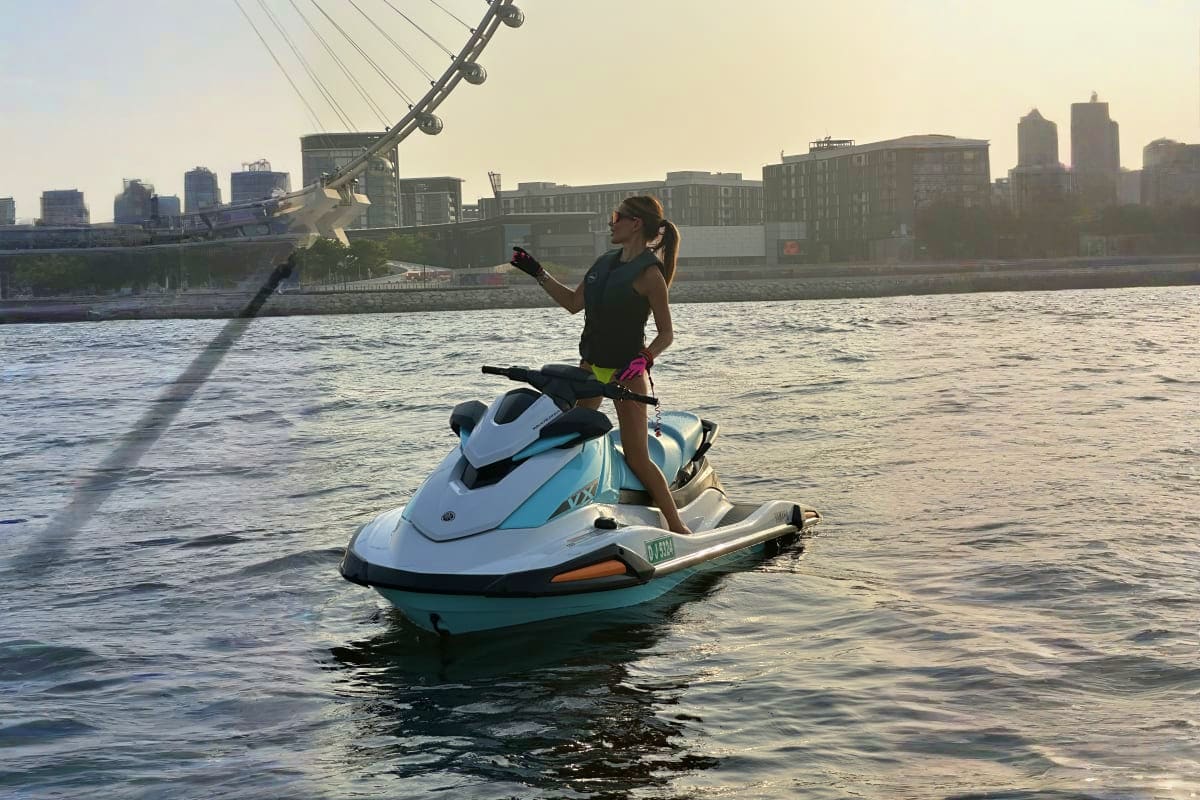 Woman riding a jet ski on water with the Millennium Bridge and London cityscape in the background