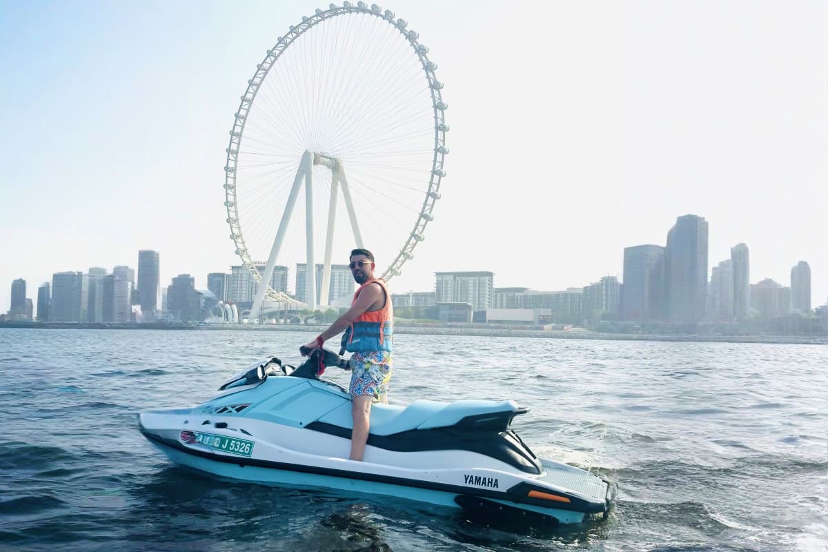 Man on Yamaha jet ski in Dubai waters with the London Eye-style Ferris wheel and city skyline in the background