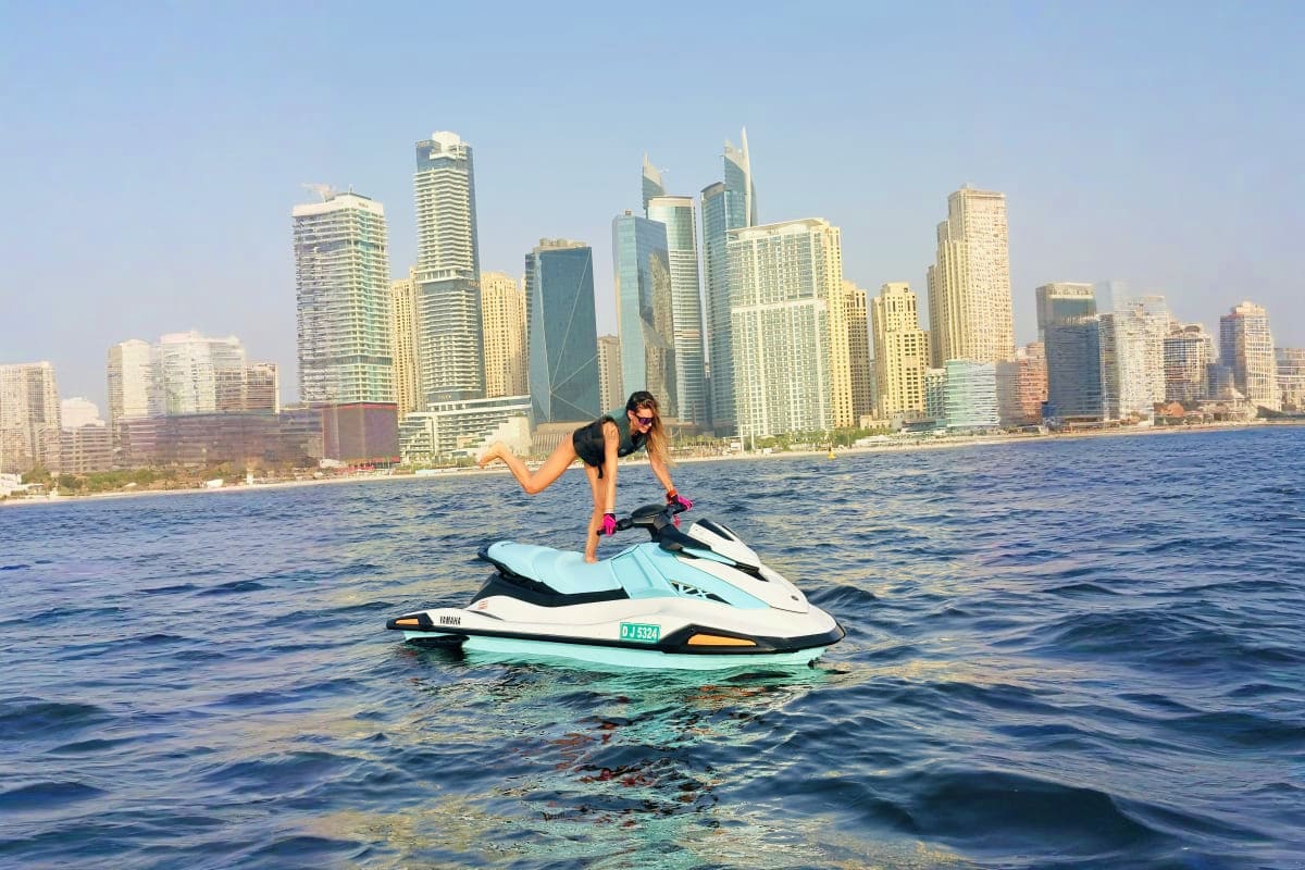 Woman riding a jet ski in Dubai waters with downtown skyline of high-rise buildings in the background