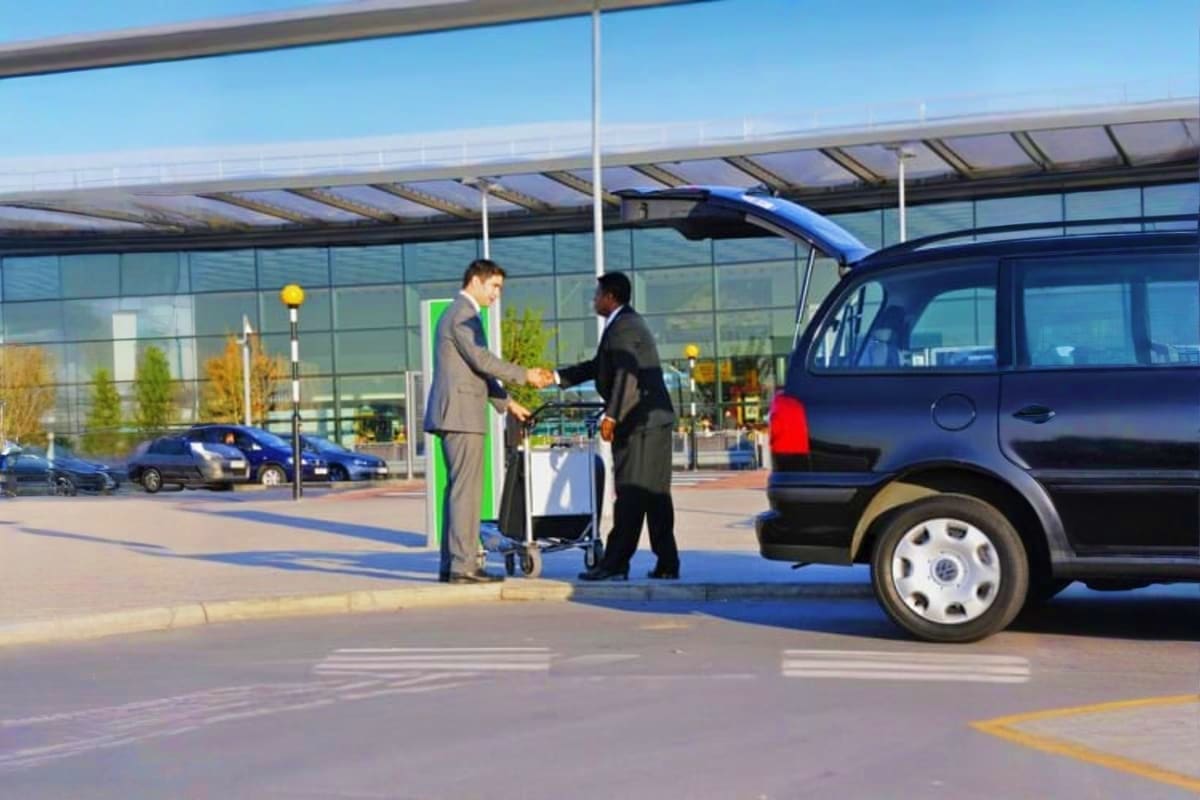 Private Half Day Sightseeing Tour Dubai Two businessmen greeting at an electric vehicle charging station at modern Dubai airport terminal with glass architecture and