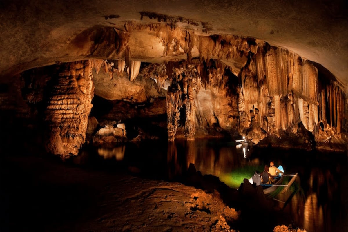 Tourist boating on underground river beneath dramatic stalactite and stalagmite formations in Puerto Princesa Subterranean Ri