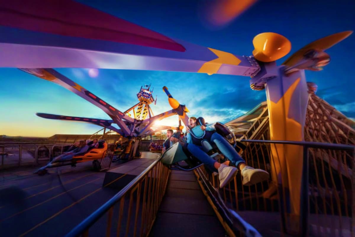 Riders experiencing the Genting Skytropolis flying adventure ride with colorful aircraft props and indoor theme park scenery