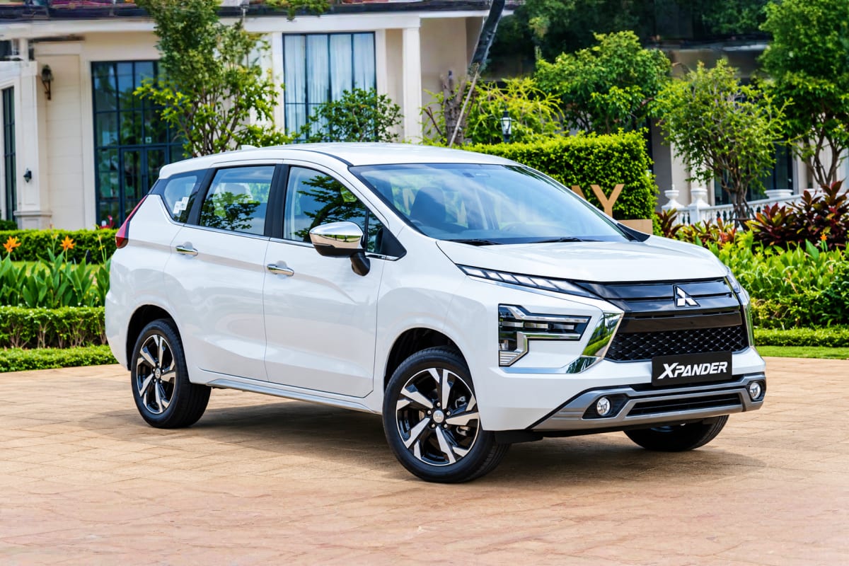 Hanoi Intracity Transfers White Mitsubishi Xpander seven-seater minivan parked in front of a modern white villa with manicured gardens