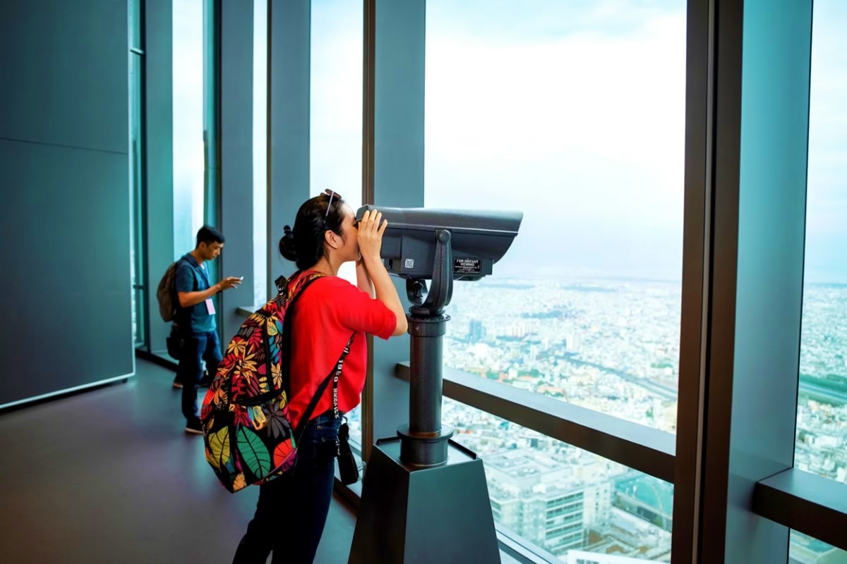 Landmark 81 Saigon Skyview Woman looking through a coin-operated telescope at a cityscape view from the observation deck of Landmark 81 in Ho Chi Minh C