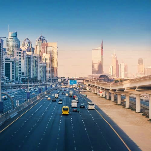 Elevated view of Dubai highway with yellow taxi, modern skyscrapers, and Sheikh Zayed Bridge during daytime