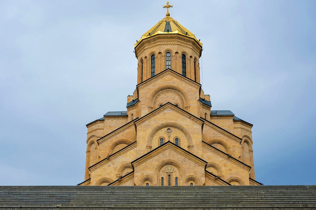 Half Day Tbilisi City Tour Golden-domed Orthodox cathedral with cream-colored stone facade and cross-topped spire against blue sky