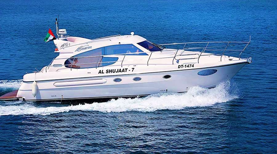 White luxury yacht Al Shujaat 7 with UAE flag cruising on blue ocean waters for deep sea fishing tours in Abu Dhabi